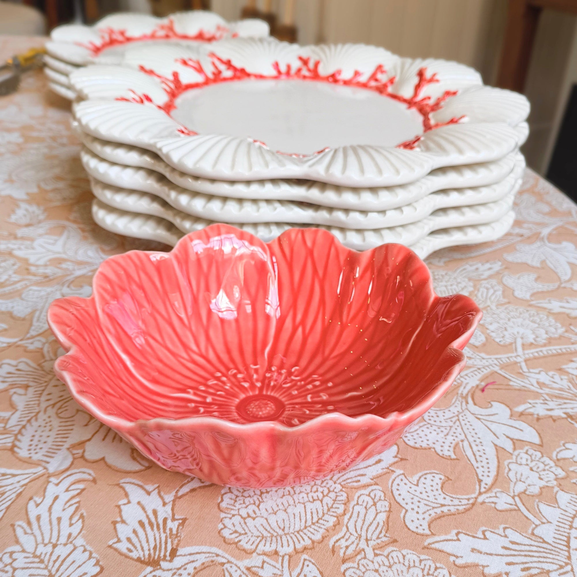 Pink decorative bowl on a floral tablecloth with white plates in the background