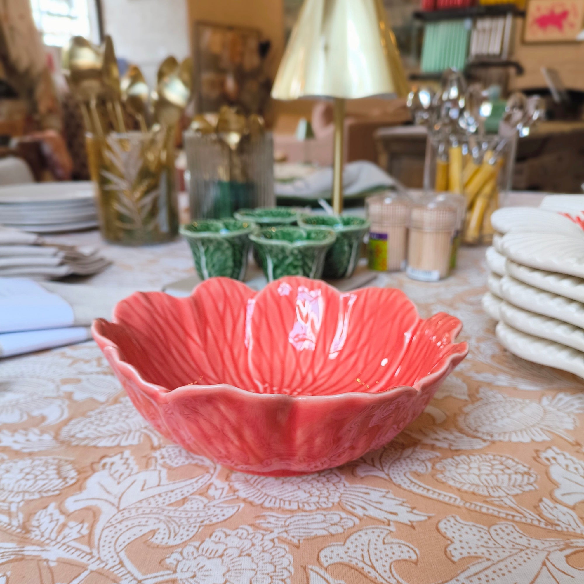 Pink ceramic bowl on a patterned tablecloth with a blurred background of kitchen items.
