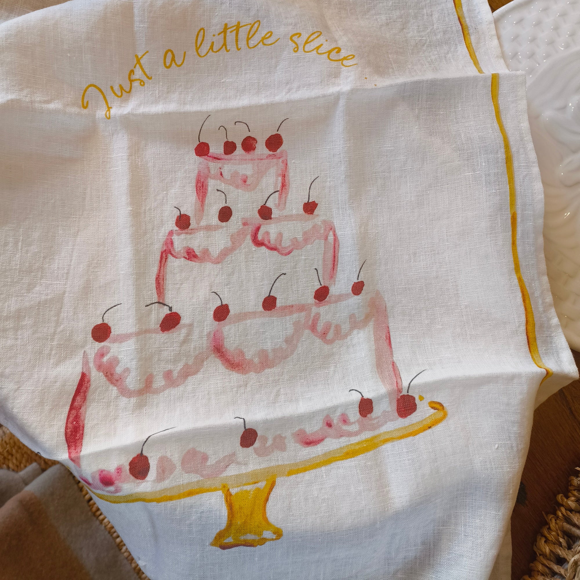 just a little slice slogan with a tier cake print on linen teatowel