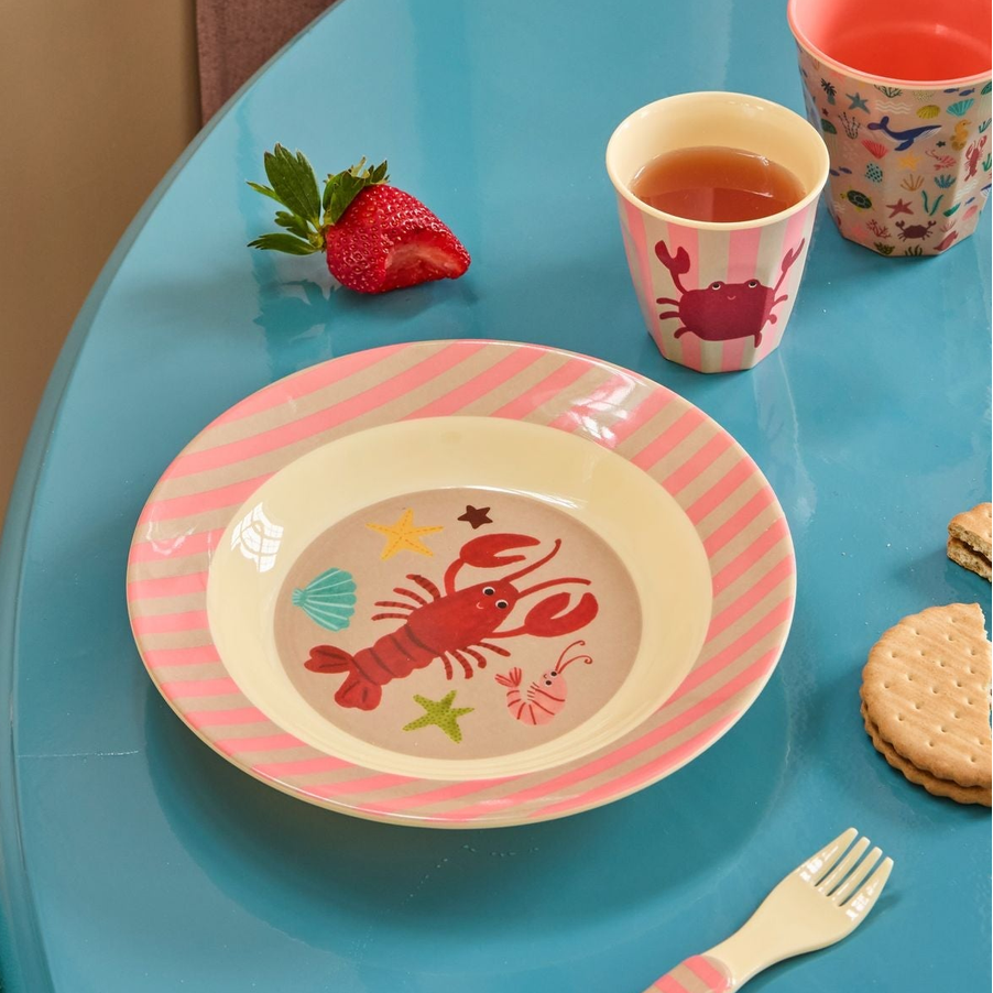 Children's table setting with a plate, cup, and fork on a blue table.