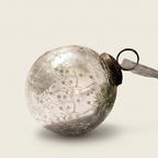 Decorative glass ball ornament with textured surface on a beige background