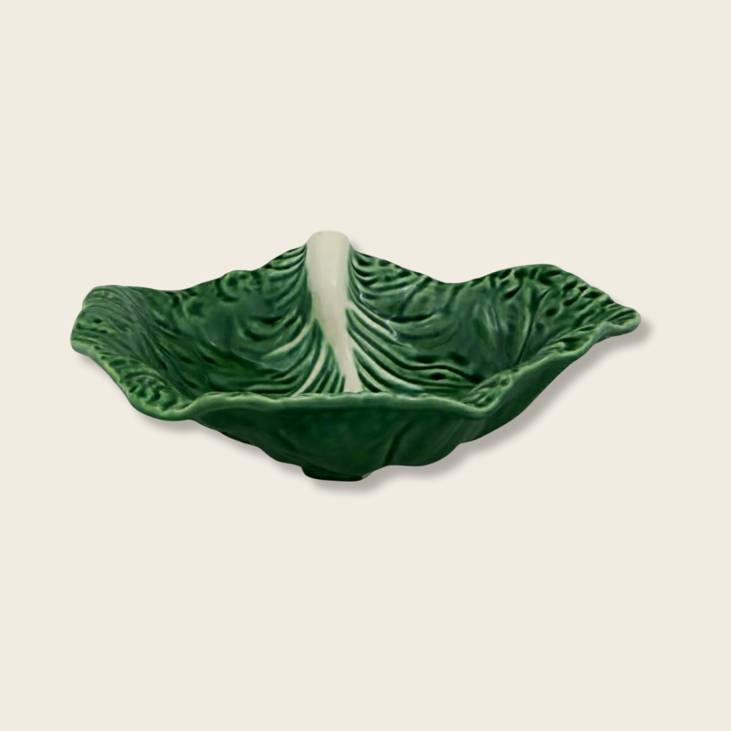 Green ceramic leaf-shaped dish on a beige background