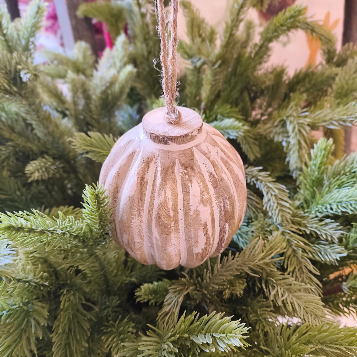 large wooden bauble with twine hanging on a Christmas tree