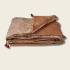 Folded brown blanket with textured pattern on a beige background