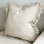 Beige pillow with ruffled edges on a neutral background