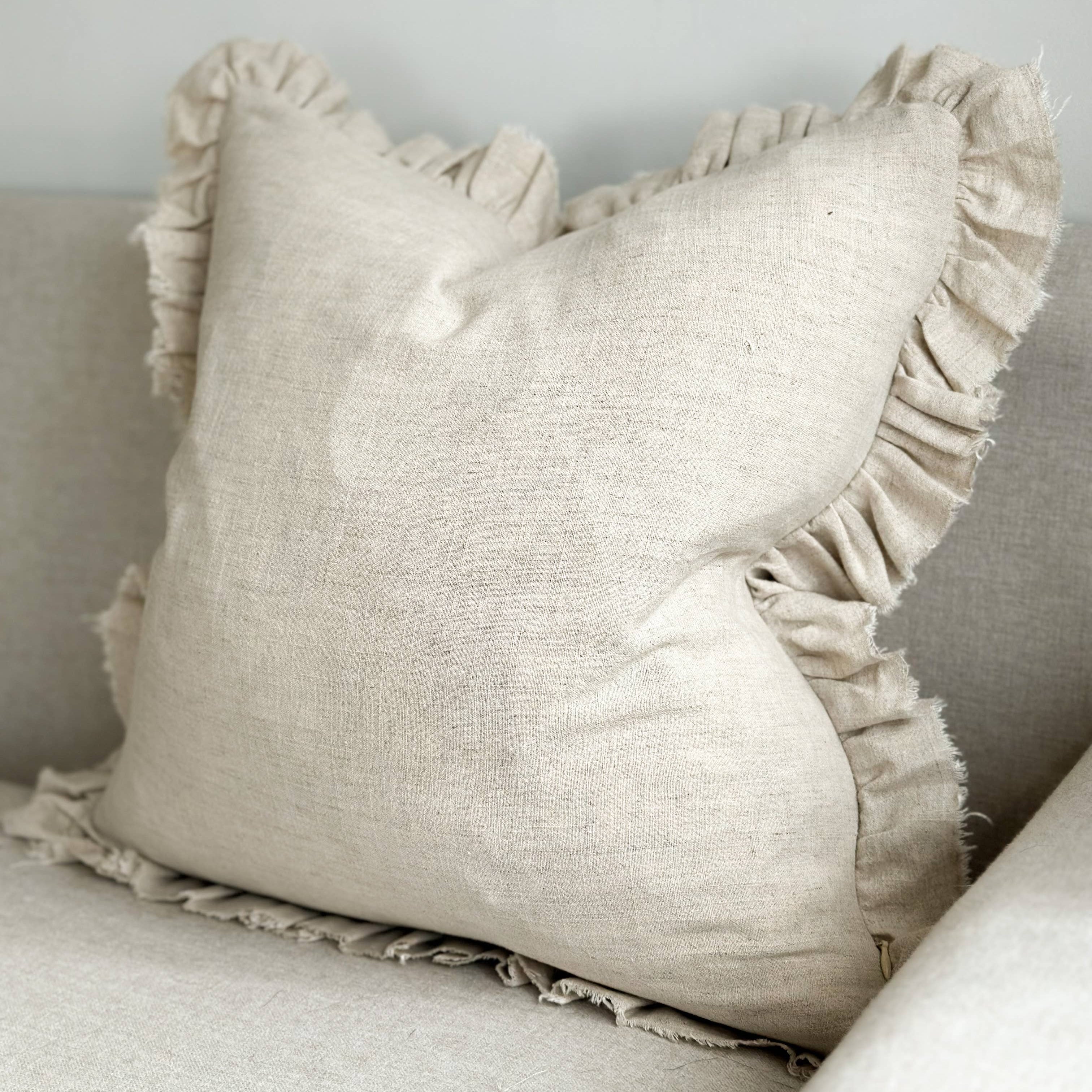 Beige pillow with ruffled edges on a neutral background