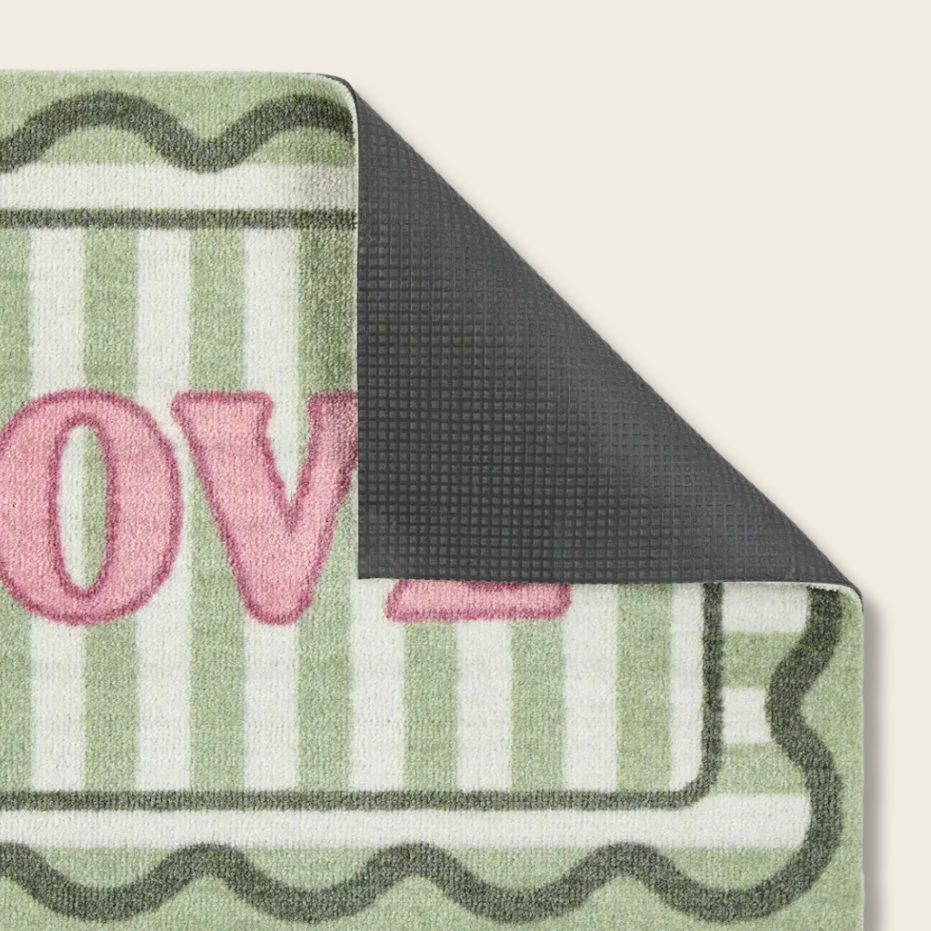 Green and white striped rug with pink letters spelling 'LOVE' on a beige background
