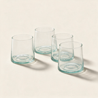 Set of four low glasses in recycled glass on a cream background