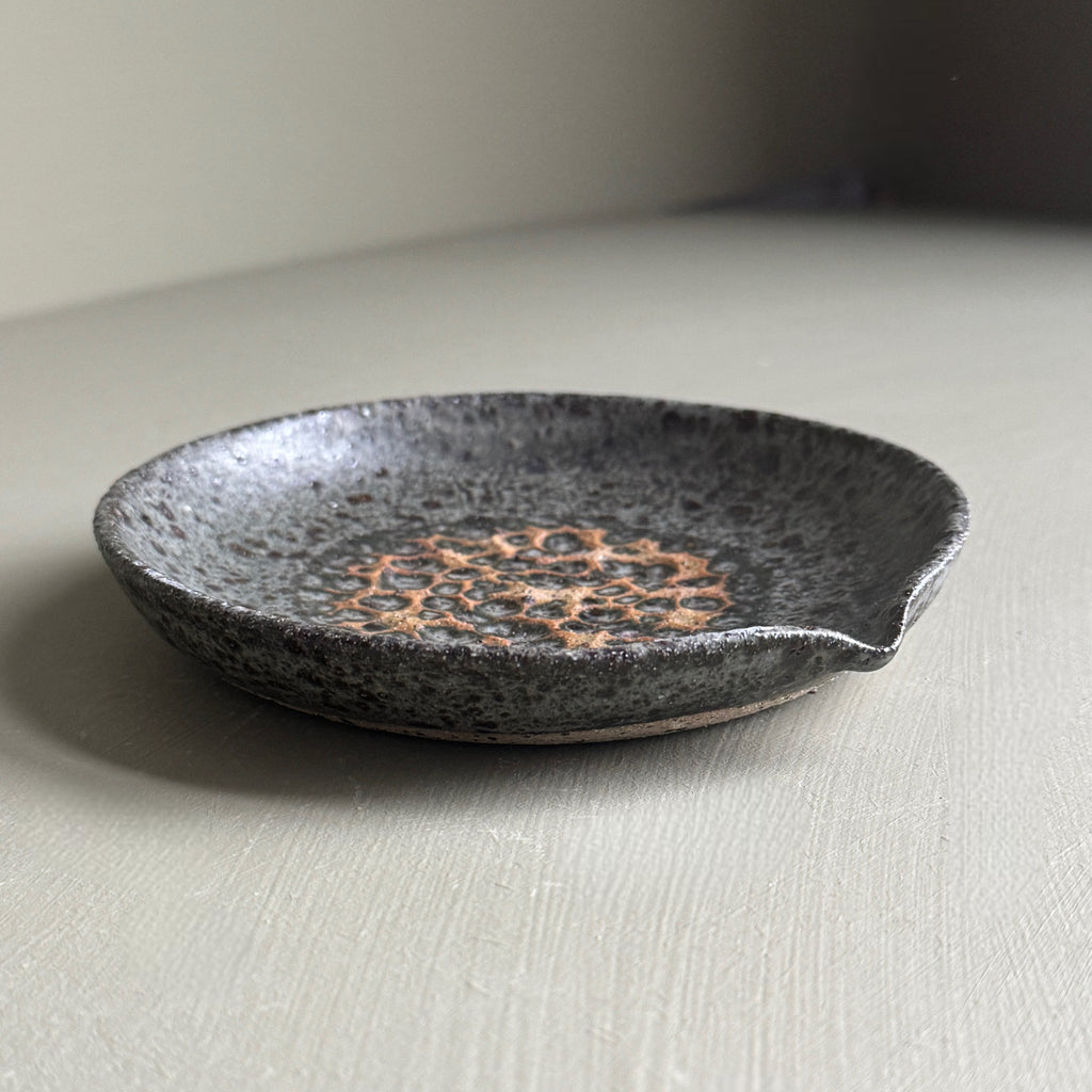 Speckled ceramic dish on a light surface with a neutral background