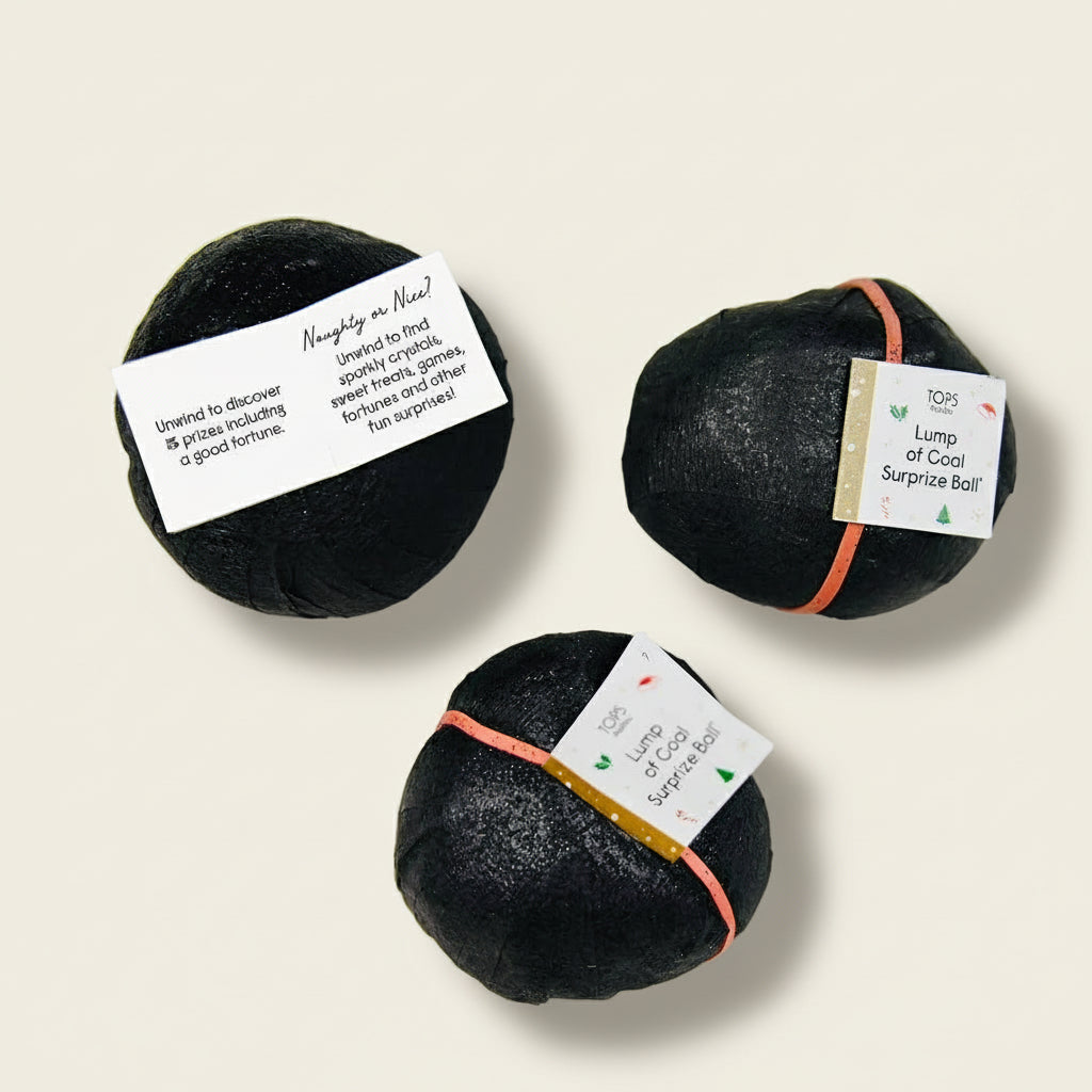 Three black bath bombs with labels on a light gray background