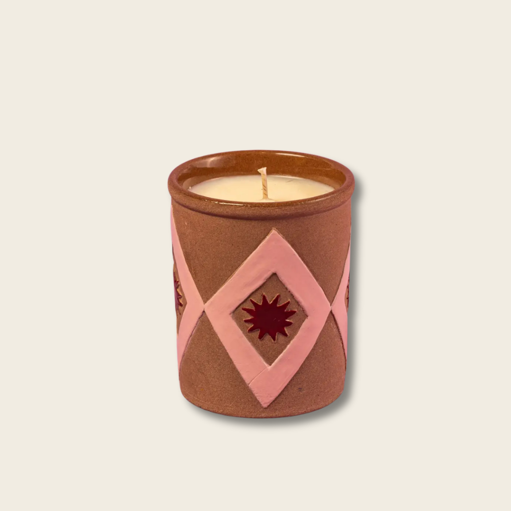 Candle in a decorative terracotta container with pink geometric design on a beige background