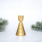 Gold bell-shaped candle holder with greenery on a white background