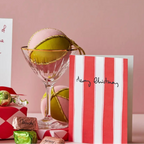 Christmas-themed gift set with a card, candy, and decorative items on a pink background