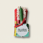 Set of colorful candles in a holder with 'the colour emporium' label on a white background
