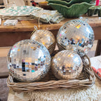 Silver disco balls in a woven basket on a table with a colorful rug underneath