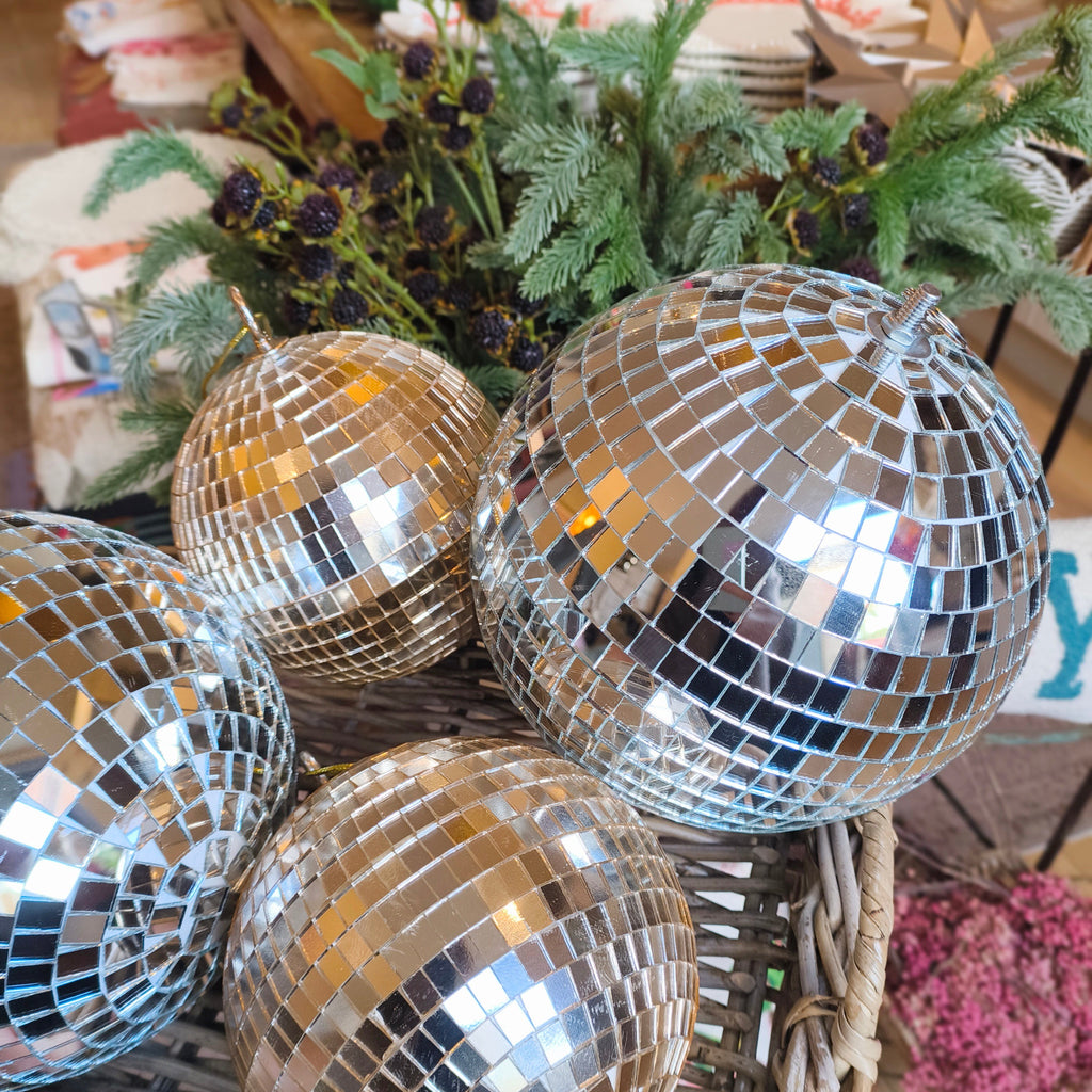 Silver and gold disco balls in a wicker basket with a blurred indoor background