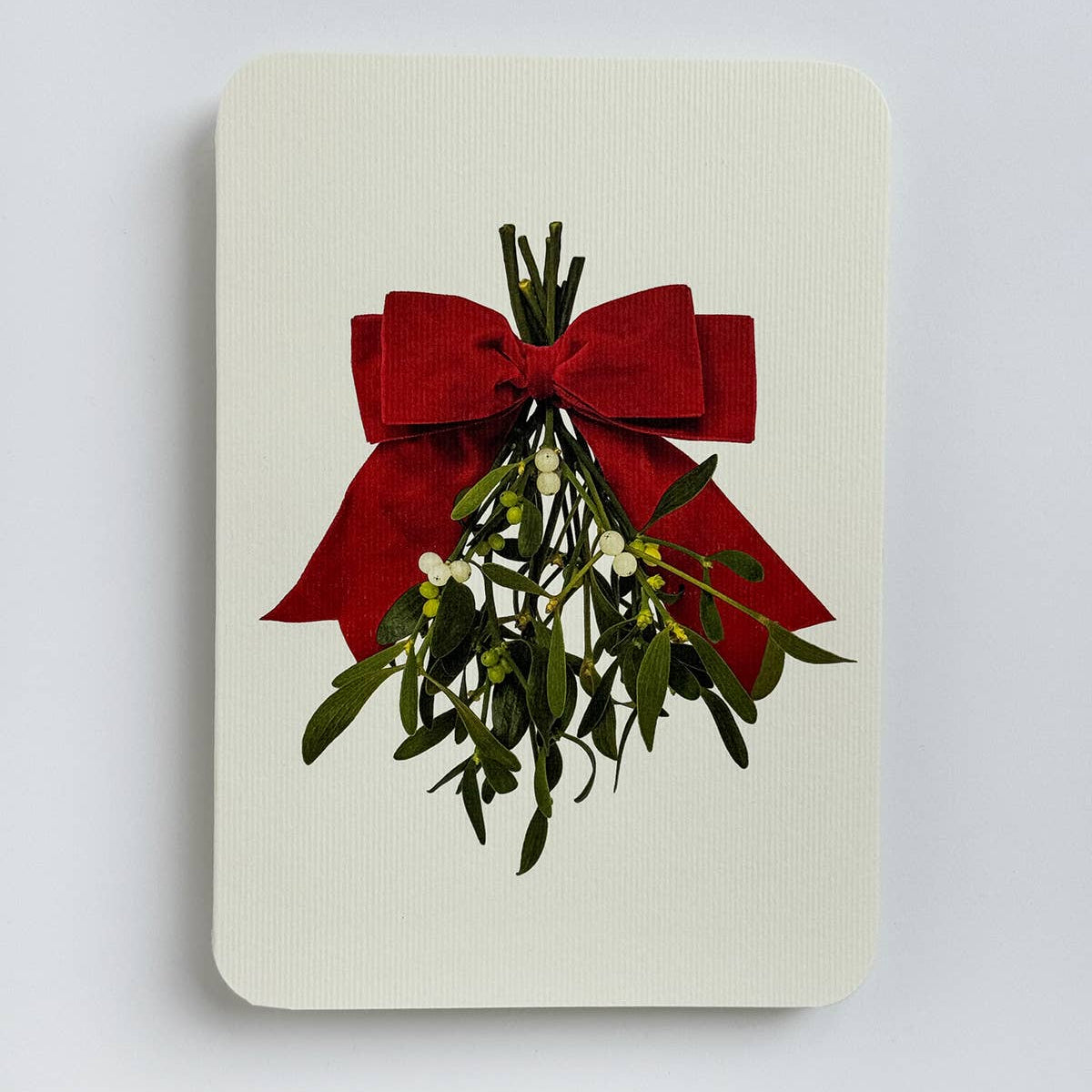 Card with mistletoe and red bow on a light gray background