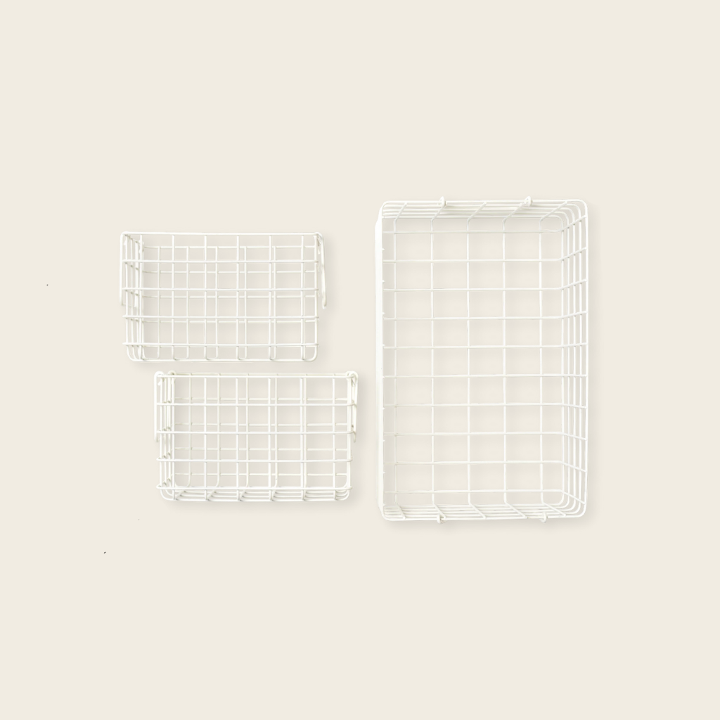 Three white wire baskets of different sizes on a beige background