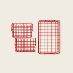 Three red wire baskets of different sizes on a beige background