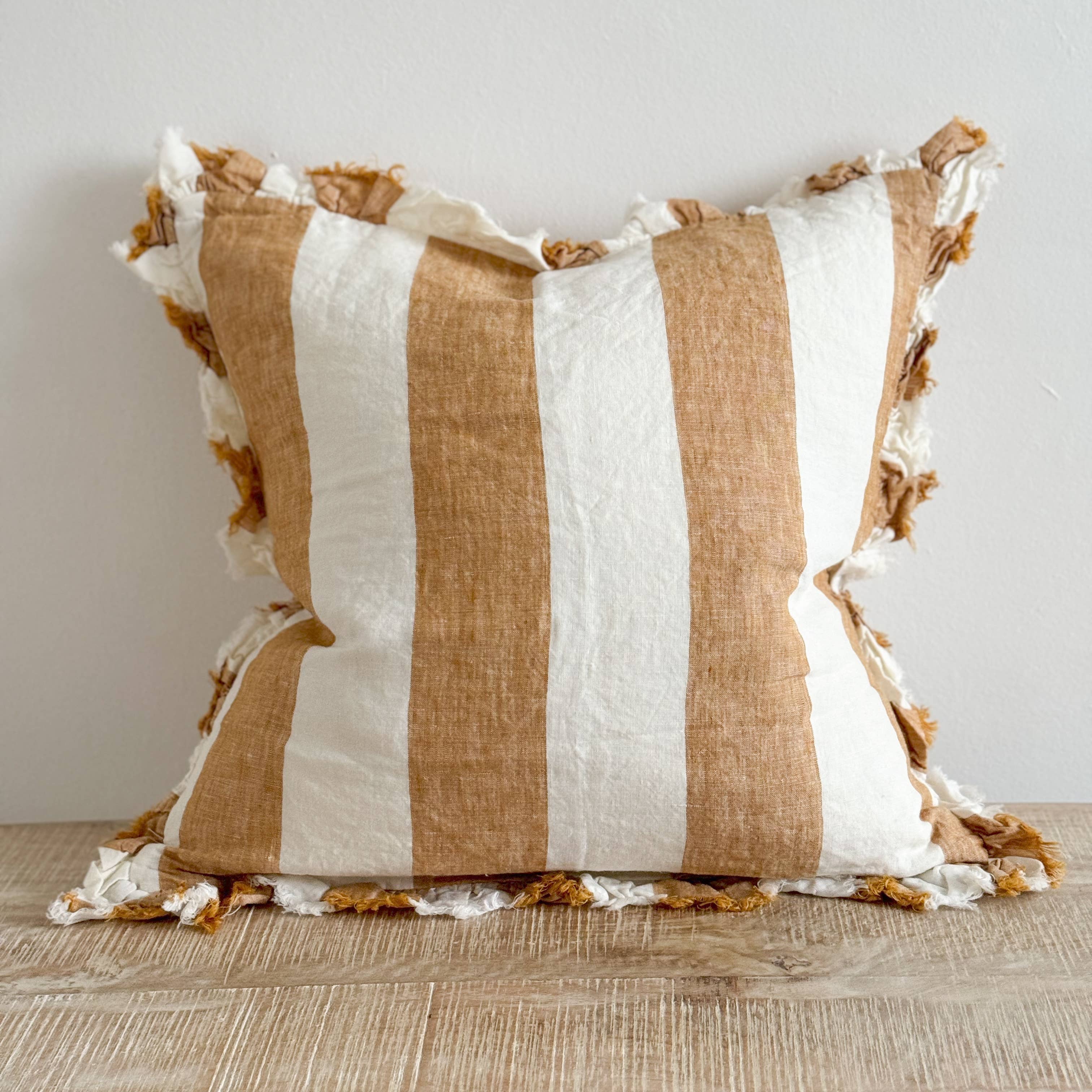 Striped pillow with brown and white stripes on a wooden surface.