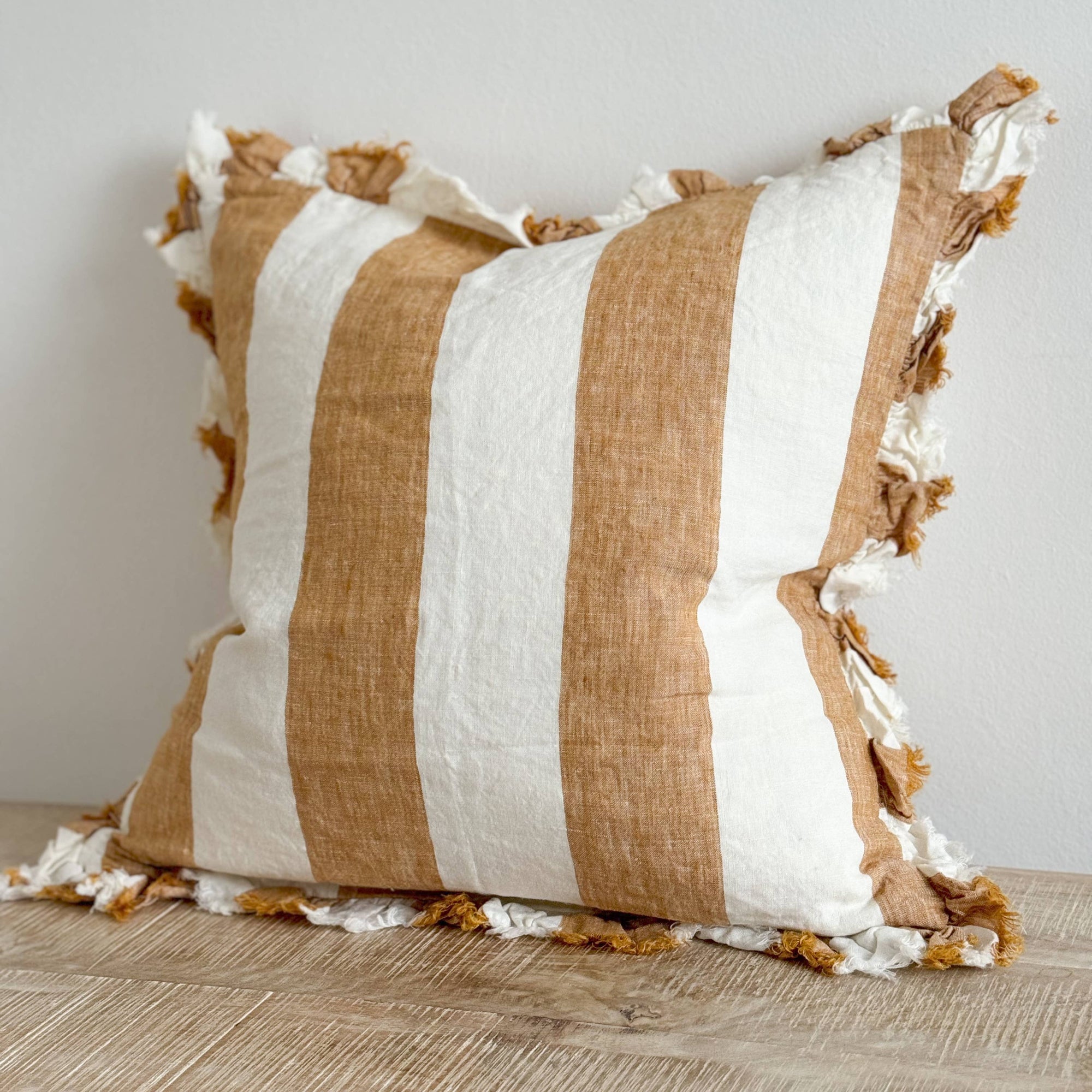 Striped pillow with brown and white colors on a wooden surface.