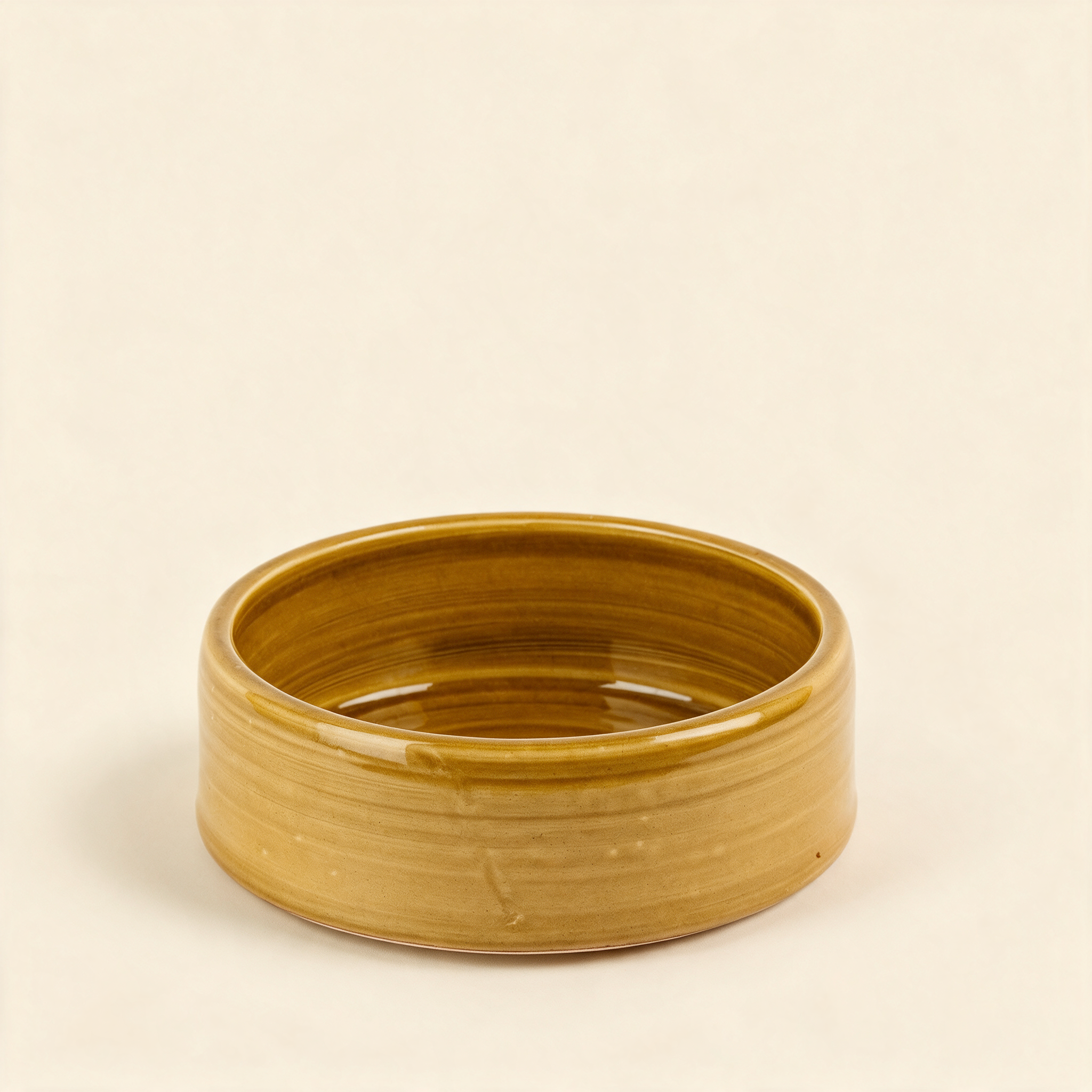 Handmade ochre stoneware dog bowl, medium, on a cream background