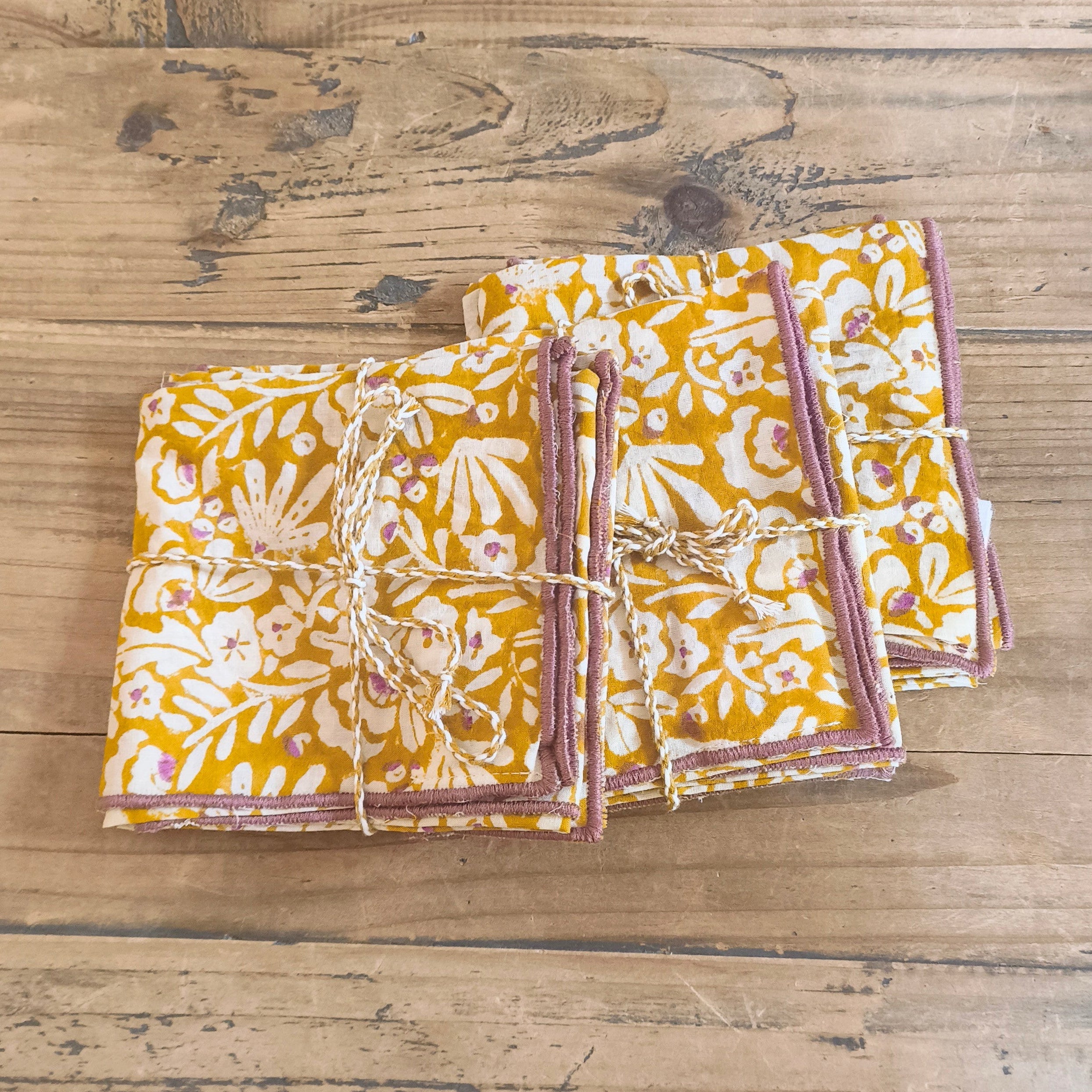 Set of folded fabric napkins with floral pattern on a wooden surface