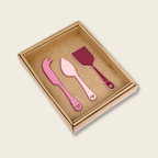 Set of pink and red cake knives in a cardboard box on a beige background
