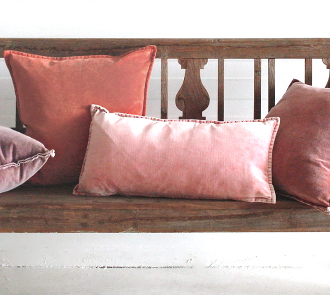 Velvet cushions in warm tones on a wooden bench