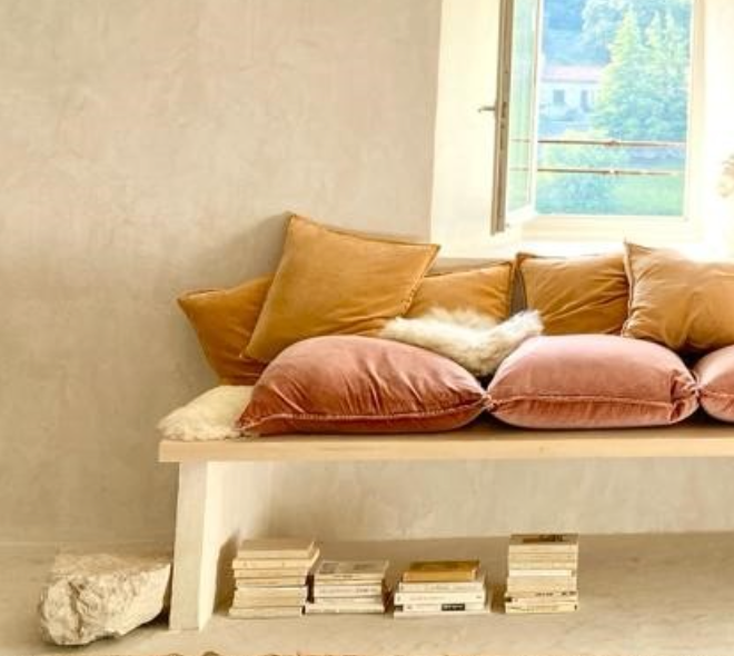 Velvet cushions in warm tones on a pale bench