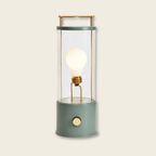 Decorative portable light with a glass cover and brass accents on a beige background