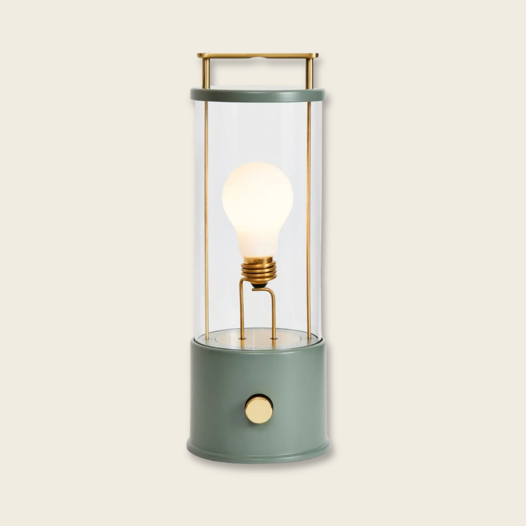 Decorative portable light with a glass cover and brass accents on a beige background