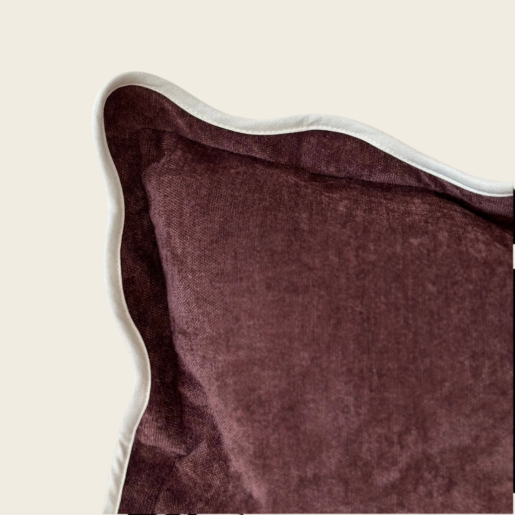 Close-up of a plum pillow with a white border on a beige background