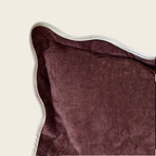 Close-up of a plum pillow with a white border on a beige background