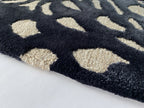 Close up of the Pluma ink rug showing the cut and loop pile and scattered motifs