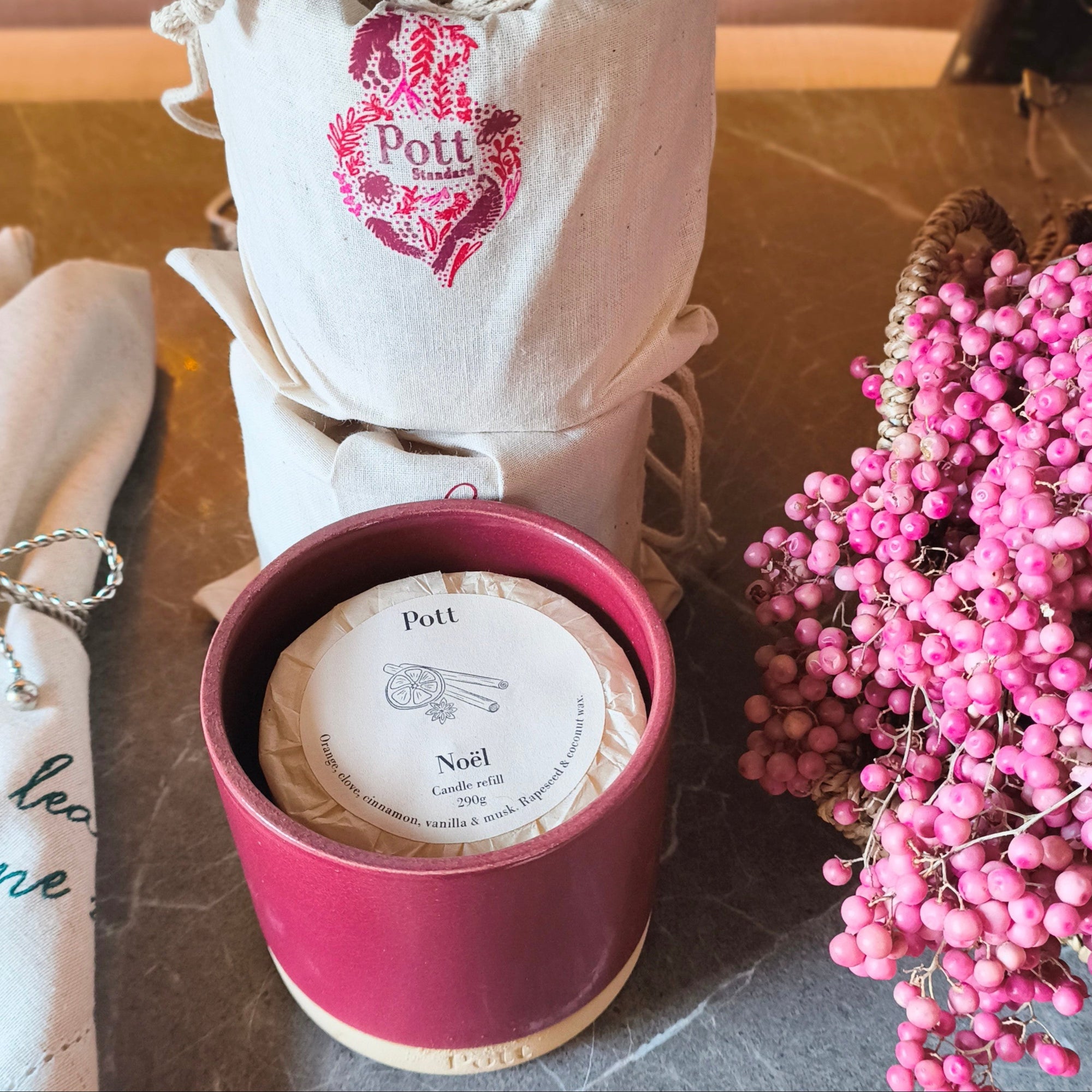 Candle with packaging and pink berries on a table