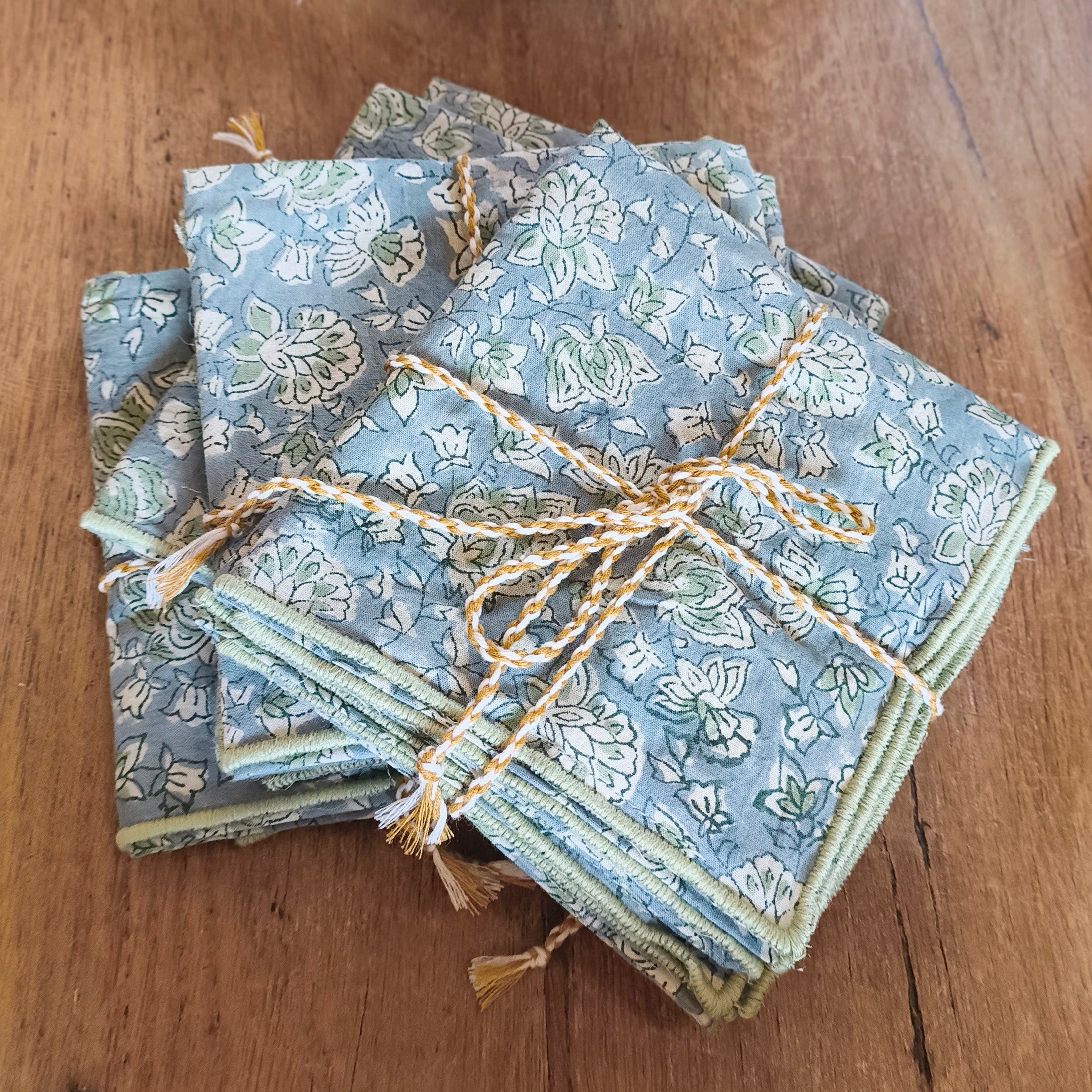 Stack of blue patterned napkins tied with twine on a wooden surface