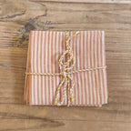 Packaged fabric napkin with striped string on a wooden surface