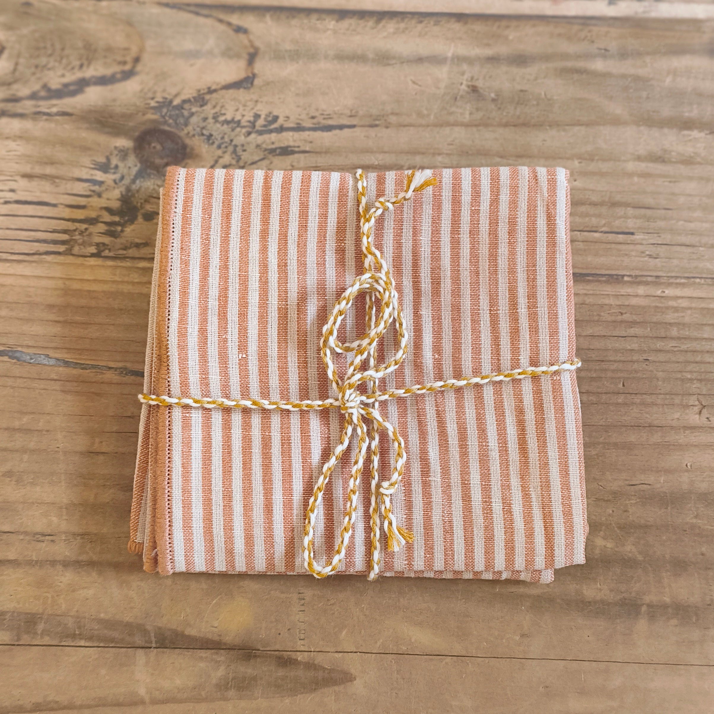Packaged fabric napkin with striped string on a wooden surface