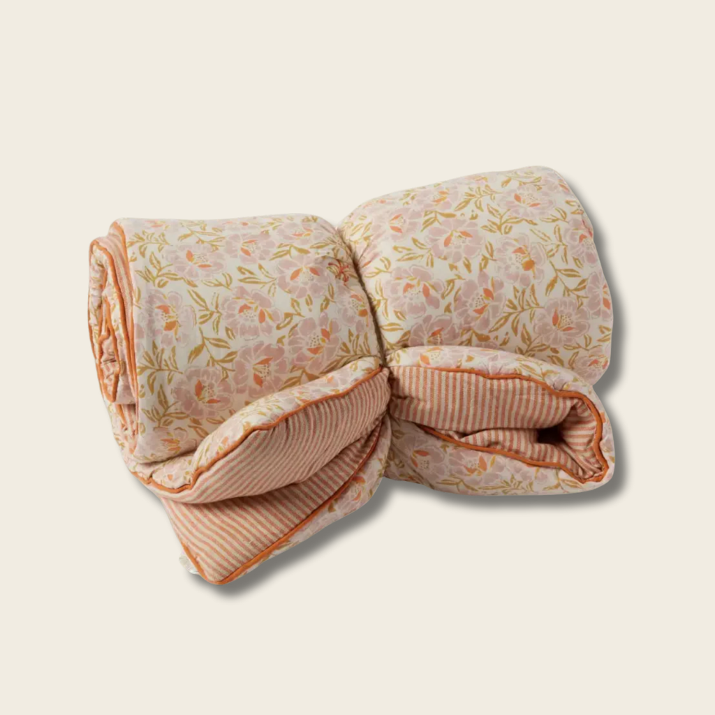Folded quilt with floral and striped patterns on a beige background