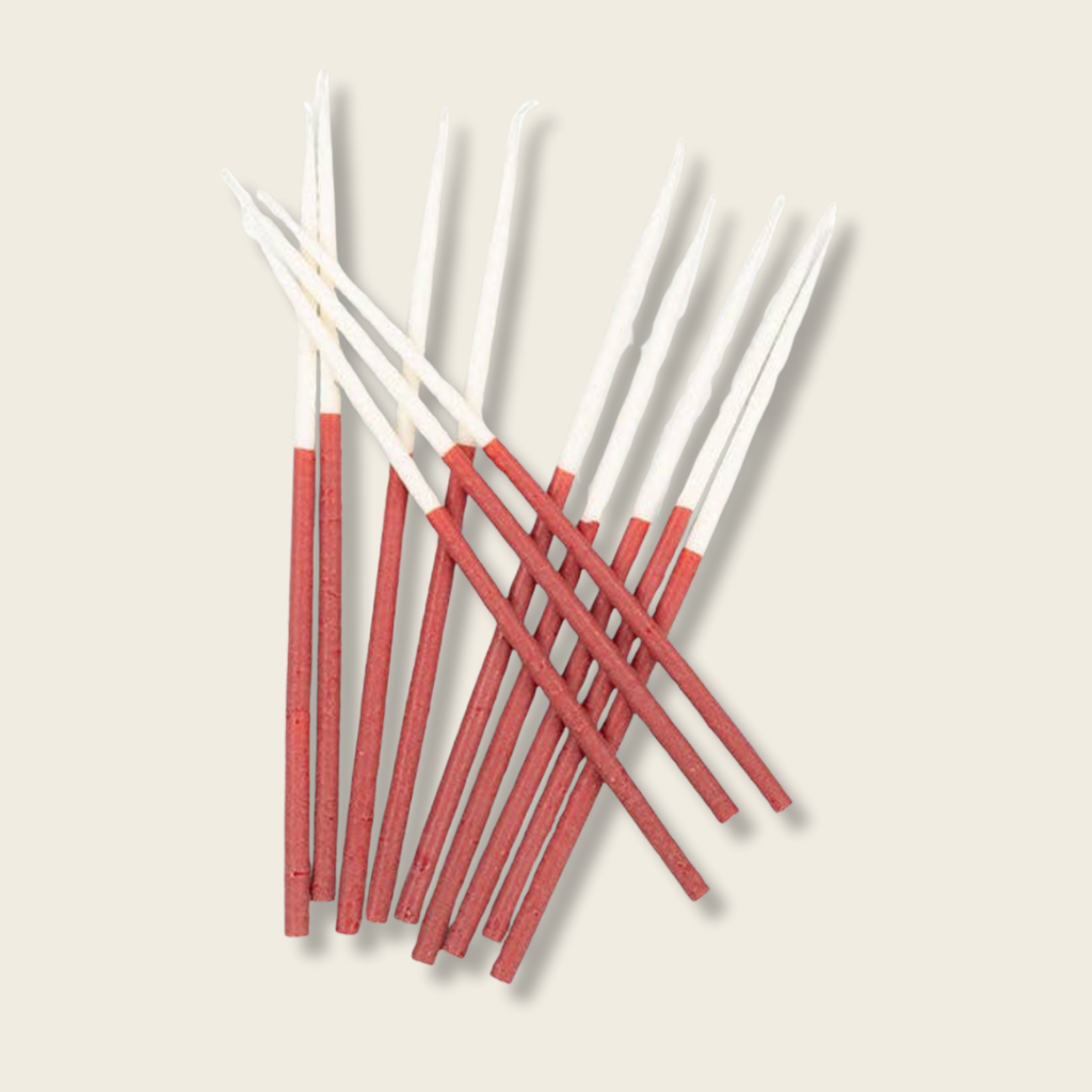 Red and white thin taper candles on a beige background
