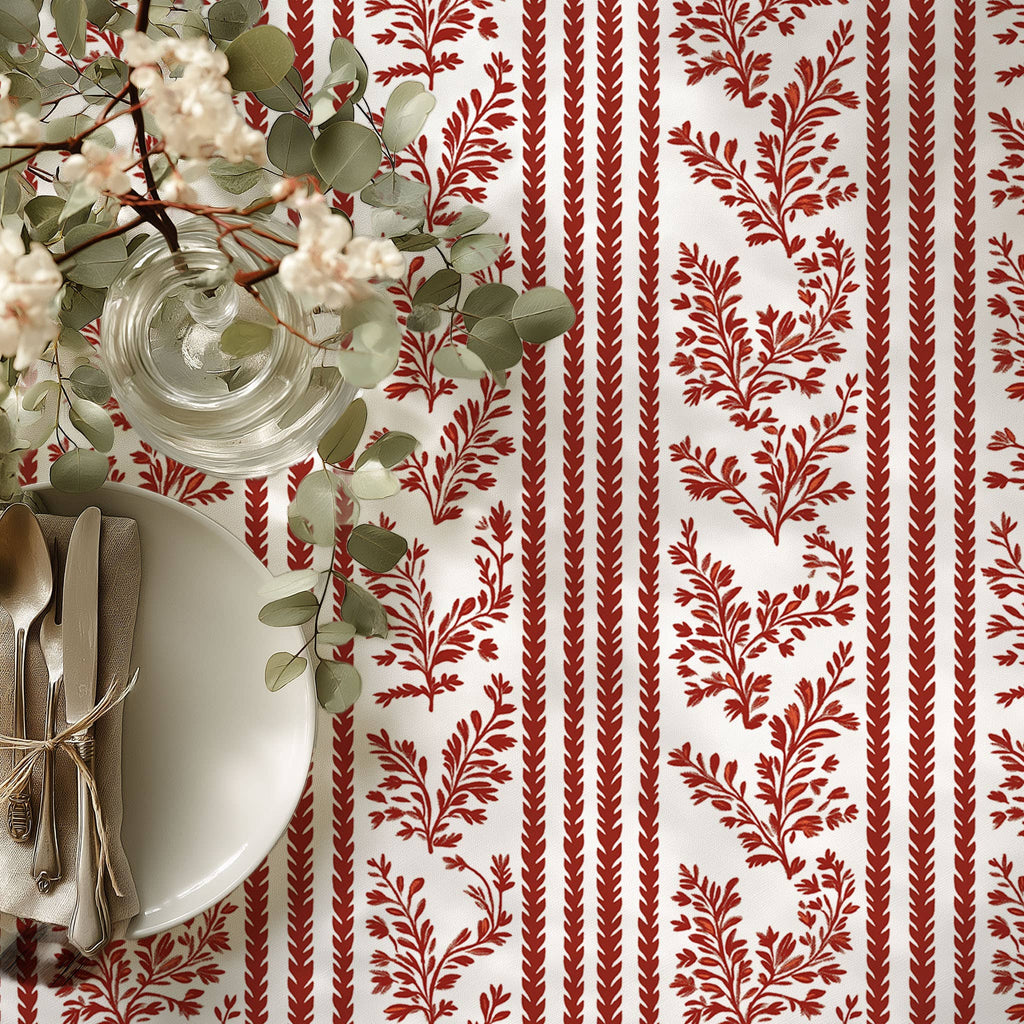Table setting with red and white patterned tablecloth, white plates, and silverware.
