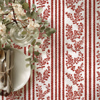 Table setting with red and white patterned tablecloth, white plates, and silverware.