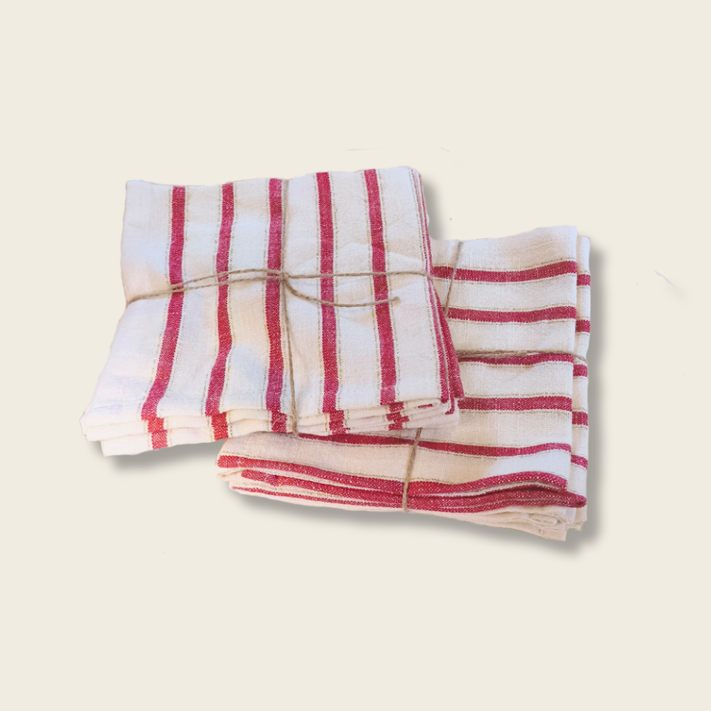 Stack of white plates with a red and white striped cloth on top, placed on a wooden surface.