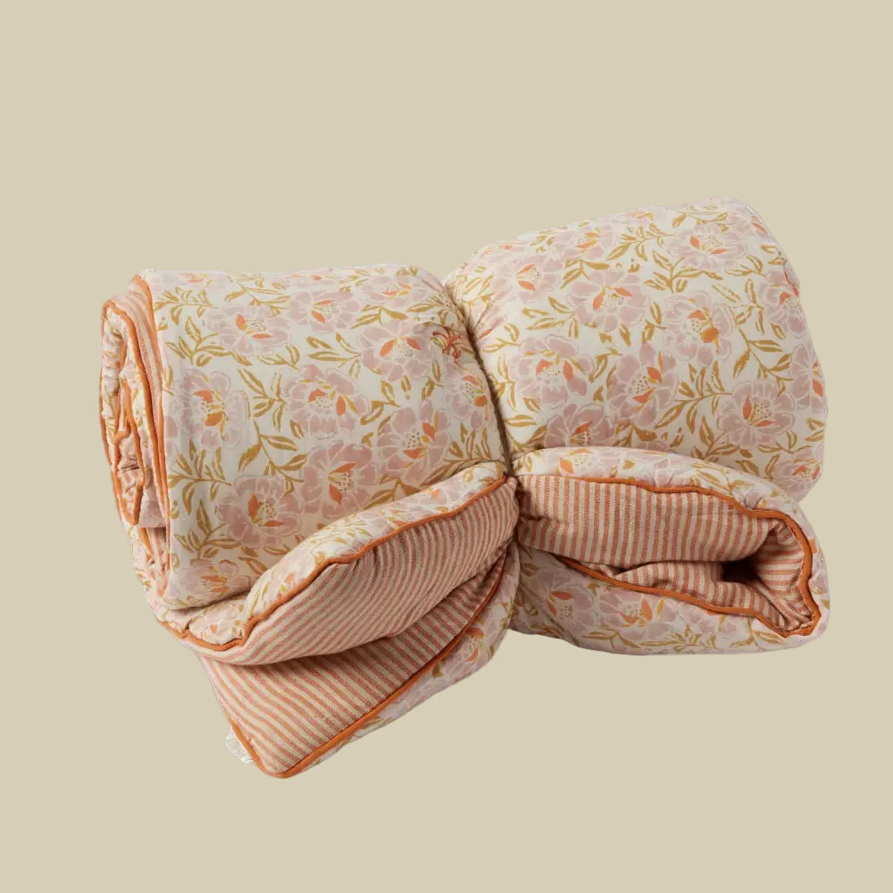 Folded quilt with floral and striped patterns on a white background