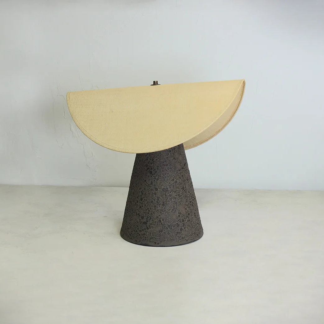 Modern lamp with a beige semi-circular shade and black textured base on a white background