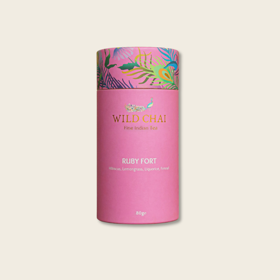 Pink cylindrical tea canister with colorful lid on a beige background