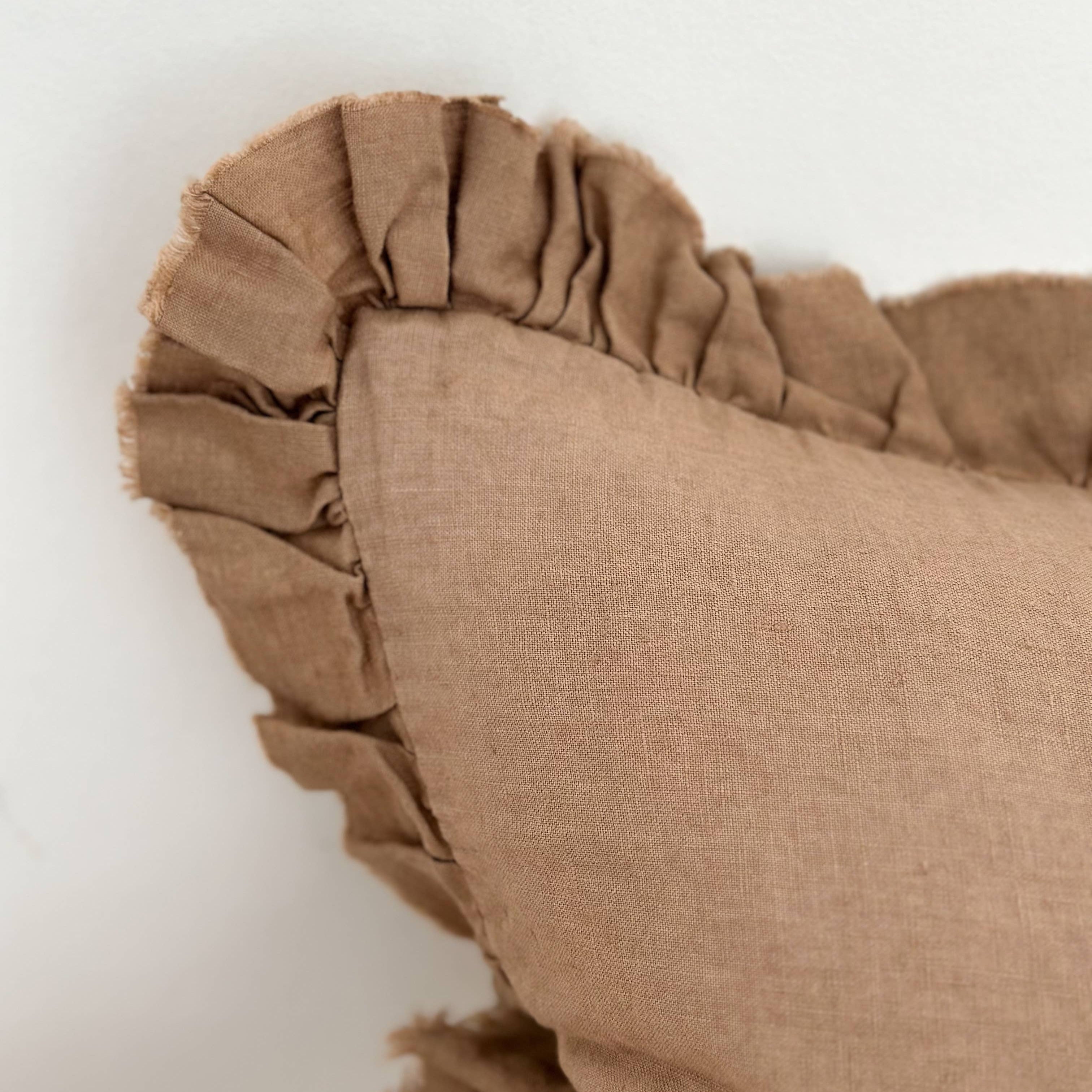 Brown pillow with ruffled edge on a white background