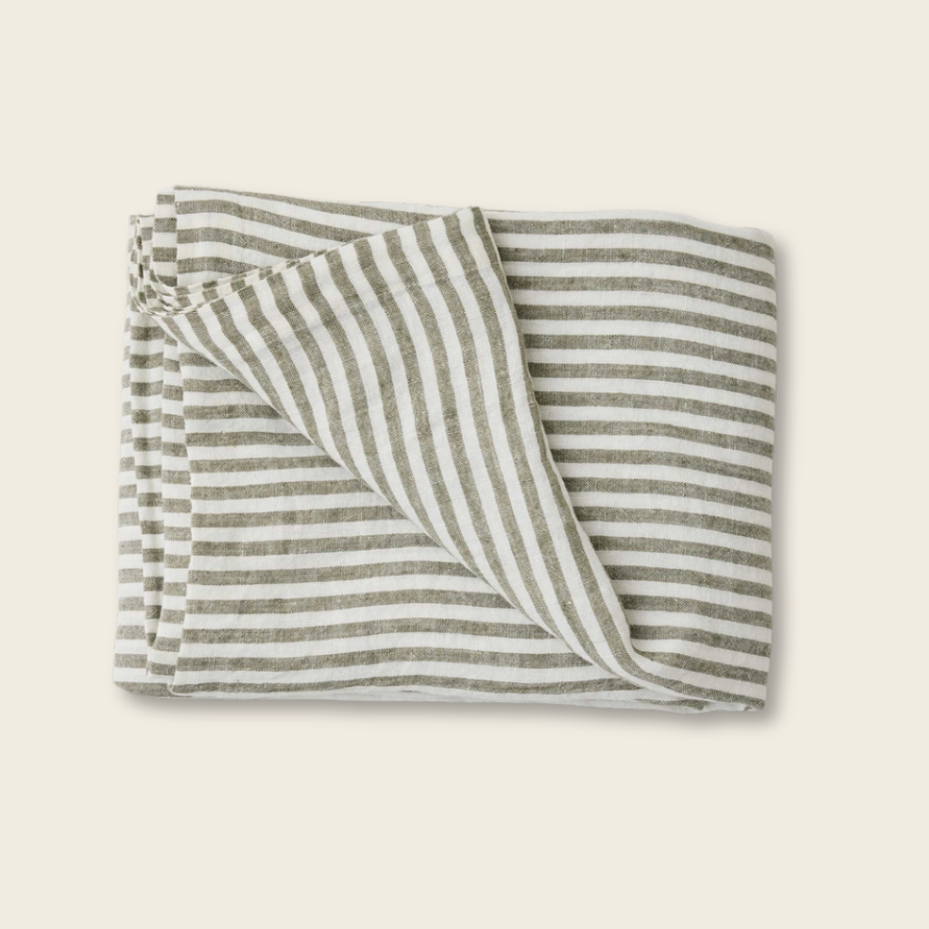 Folded striped fabric with green and white lines on a beige background