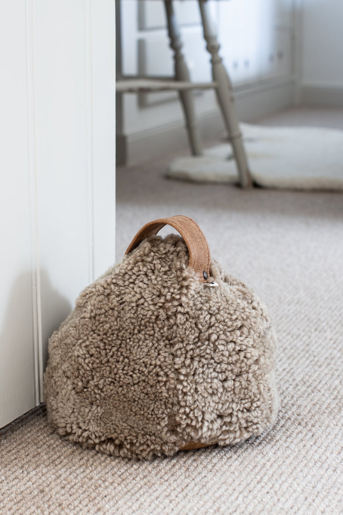 Brown cropped sheepskin door stop with a leather handle